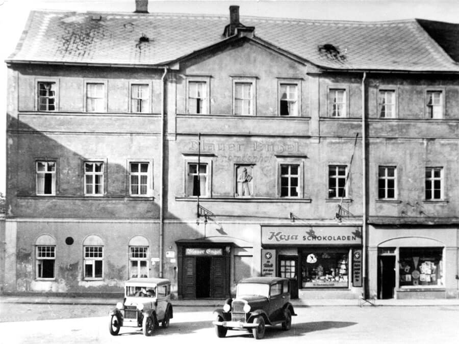 Das Originalgebäude aus dem 16. Jahrhundert hatte über die Jahrhunderte unter anderem das Hotel „Blauer Engel“ beherbergt sowie einen Verlag mit Buchdruckerei. In den Sechzigern wurde es abgerissen und durch einen nüchternen Neubau ersetzt. 